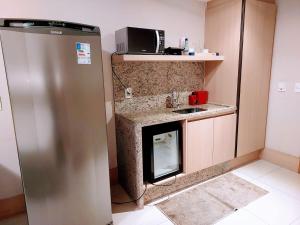 a small kitchen with a refrigerator and a microwave at Flat Cullinan Brasília SL in Brasilia
