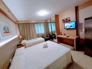 a hotel room with two beds and a television at Flat Cullinan Brasília SL in Brasilia