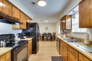 a kitchen with wooden cabinets and a black refrigerator at Bright Tallahassee Vacation Rental Near FSU and FAMU in Tallahassee