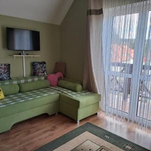 a living room with a green couch and a large window at Domki Oaza Spokoju Berezka in Berezka