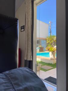 - une chambre avec une porte coulissante en verre menant à une piscine dans l'établissement Suite cantinho do sossego, à Arraial do Cabo