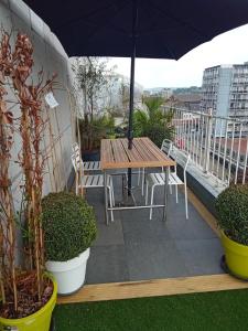 una mesa de madera y sillas en un balcón con sombrilla en Liège centre Médiacité appartement parking gratuit terrasse immense 8ème pour 2 personnes, en Lieja
