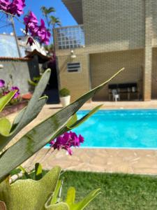 una piscina con flores púrpuras frente a una casa en Suite cantinho do sossego, en Arraial do Cabo