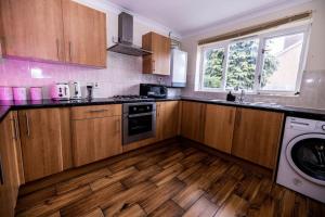 a kitchen with wooden cabinets and a washer and dryer at Pristine Relocation House in London