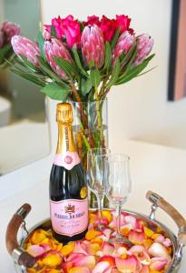 butelka wina i kieliszki na stole z kwiatami w obiekcie 7 on Marine w mieście Hermanus