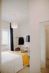 a white bedroom with a bed with a yellow blanket at Casa GINA a 2 passi dal mare in Terracina