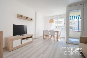sala de estar con TV y mesa con sillas en Apartamento Miramar by MarCalma, en Torredembarra