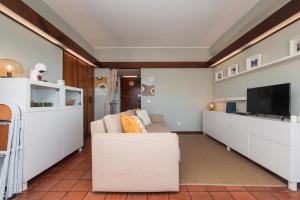 a living room with a white couch and a tv at Sesimbra 1111 in Sesimbra
