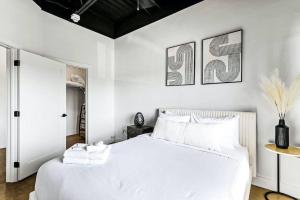 1 dormitorio con 1 cama blanca y 2 cuadros en la pared en Brand New Condo near downtown Nash w washer dryer en Nashville