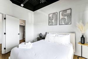 een slaapkamer met een wit bed en twee foto's aan de muur bij Brand New Condo near downtown Nash w washer dryer in Nashville