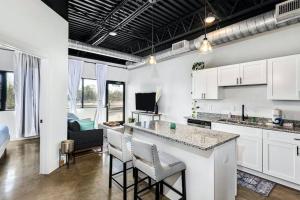 a kitchen with white cabinets and a bar with stools at Brand New Condo near downtown Nash w washer dryer in Nashville