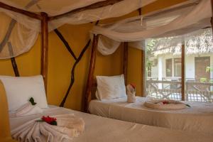 a bedroom with two beds and a window at PASHA HOTEL Zanzibar in Nungwi