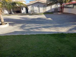 a driveway with a palm tree and a building at Vista Oceanica Pousada in Marataizes