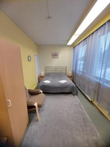 um quarto com uma cama, uma cadeira e uma janela em Hotel Ilomantsi North Star em Ilomantsi