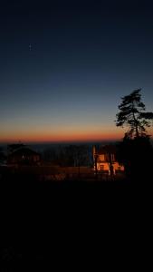 einen Sonnenuntergang mit einem Baum und einem Haus in der Ferne in der Unterkunft Les Maisons de CharlocHomes, F1 Vue Mer in Trouville-sur-Mer