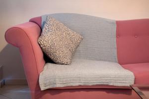 eine rosa Couch mit einem Kissen drauf in der Unterkunft Norma’s House in Khlóï