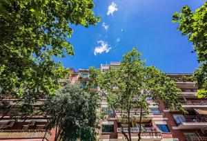 ein hohes Gebäude mit Bäumen davor in der Unterkunft Sweet Inn - Wellington in Barcelona