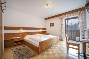 a bedroom with a bed and a desk and a window at Apartments Zilli in Laion