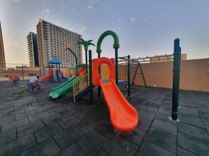 a playground with an orange slide and a green slide at Spacious Studio in IMPZ in Dubai