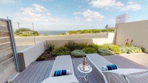 balcón con mesa, sillas y vistas al océano en 7 on Marine, en Hermanus
