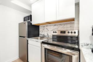 a kitchen with stainless steel appliances and white cabinets at Luxurious 4 BR townhouse in New York
