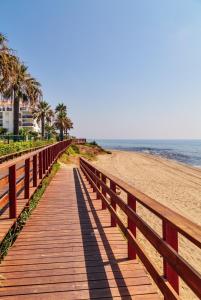 eine hölzerne Promenade, die zum Strand mit Palmen führt in der Unterkunft Casa Paraiso Calahonda in Sitio de Calahonda