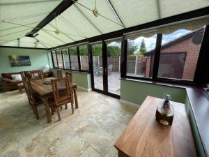 a conservatory with a wooden table and a dining room at Redd Lodge Heart of the National Forest in Thringstone