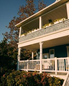 ein Haus mit einer Veranda mit Blumen darauf in der Unterkunft The Bentley Inn in Bay Head