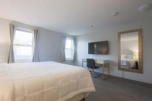 a bedroom with a bed and a desk and a mirror at Westborough Inn in Westborough