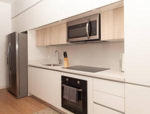 uma cozinha branca com um micro-ondas e um frigorífico em Apartamento una habitación DLX em Echeverría
