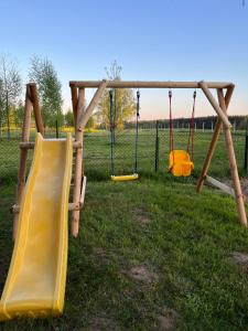 a playground with two swings and a slide at Brzozowe zacisze in Sulerzyż
