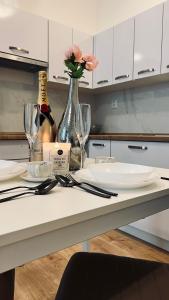 a white kitchen with a table with glasses and a bottle of wine at SOFI living in Ostrava