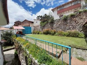 a stone wall with a blue fence next to a yard at El Jardín de Jeni in Cusco