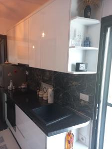 uma cozinha com armários brancos e um balcão preto em Private Villa Aras -Pleasure of Elegance & Serenity em Vlorë