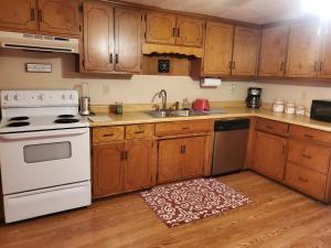 uma cozinha com armários de madeira e um forno de fogão branco em Kentucky Hills Country Cottage em Morgantown