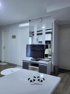 a living room with a flat screen tv and a couch at Apartment Kalibata City by PanBul in Jakarta