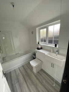 a bathroom with a toilet and a tub and a sink at CODE Terrace Oulton Broad Suffolk in Oulton