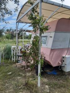 a pink and white camper with a table under a tent at Mary 's Retro Caravan in Eratini