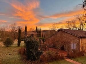 a house in a yard with a sunset in the background at La Bourdette - Elegantes Herrenhaus im Boutique Stil in Daumazan-sur-Arize