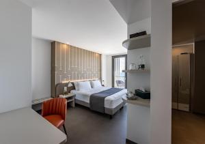 um quarto de hotel com uma cama e uma cadeira em DIVA HOTEL LIGNANO - Adults Only em Lignano Sabbiadoro