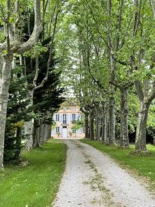 a dirt road with trees and a house in the background at La Bourdette - Elegantes Herrenhaus im Boutique Stil in Daumazan-sur-Arize