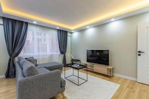 ein Wohnzimmer mit einem Sofa und einem TV in der Unterkunft Modern and Well Designed Apartment Near Public Transportation in Maltepe in Istanbul