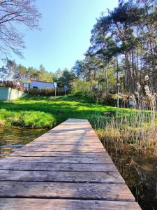 un ponte di legno su un corpo idrico di Apartament Baranek Nad Jeziorem a Gostycyn