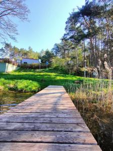 a wooden bridge over a body of water at Apartament Baranek Nad Jeziorem in Gostycyn