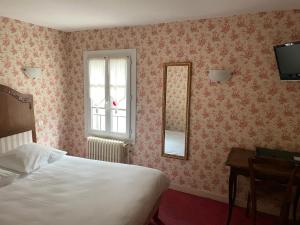 1 dormitorio con cama, ventana y espejo en Le Coq d'Or, en Brive-la-Gaillarde
