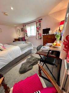 a bedroom with a bed and a desk with a table at Vine Cottage in Farnham