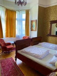 sypialnia z 2 łóżkami, krzesłem i oknem w obiekcie Villa Luca w mieście Mosonmagyaróvár