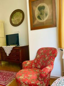 uma sala de estar com uma cadeira vermelha e uma televisão em Villa Luca em Mosonmagyaróvár