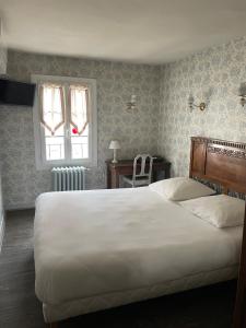 Un dormitorio con una gran cama blanca y una ventana en Le Coq d'Or, en Brive-la-Gaillarde