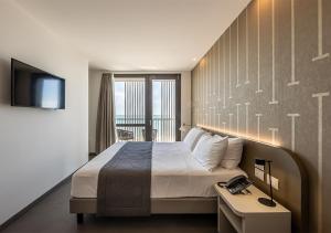 ein Hotelzimmer mit einem Bett und einem TV in der Unterkunft DIVA HOTEL LIGNANO - Adults Only in Lignano Sabbiadoro